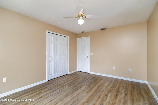 unfurnished bedroom with ceiling fan, a closet, and light hardwood / wood-style floors