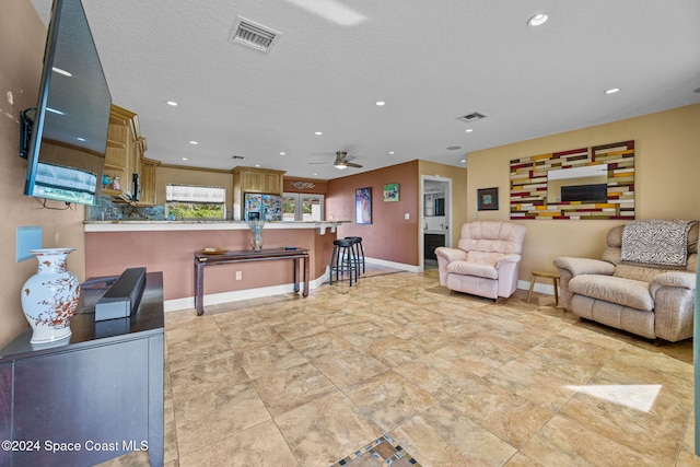 living room featuring ceiling fan and a textured ceiling