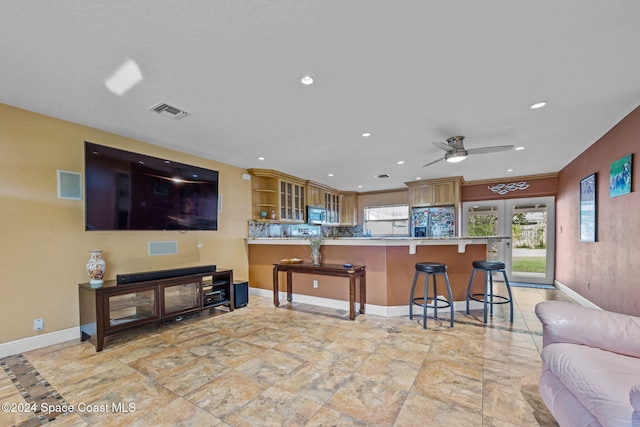 kitchen with ceiling fan, tasteful backsplash, black fridge, kitchen peninsula, and a breakfast bar area