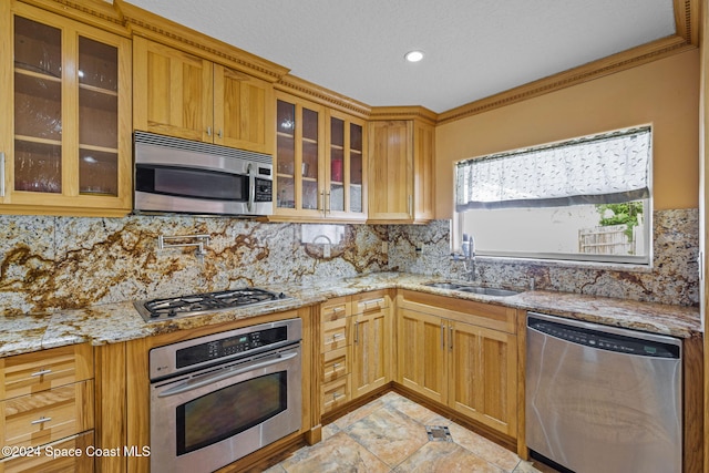 kitchen featuring decorative backsplash, appliances with stainless steel finishes, light stone counters, crown molding, and sink