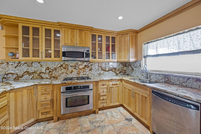 kitchen featuring appliances with stainless steel finishes, tasteful backsplash, light stone counters, and sink