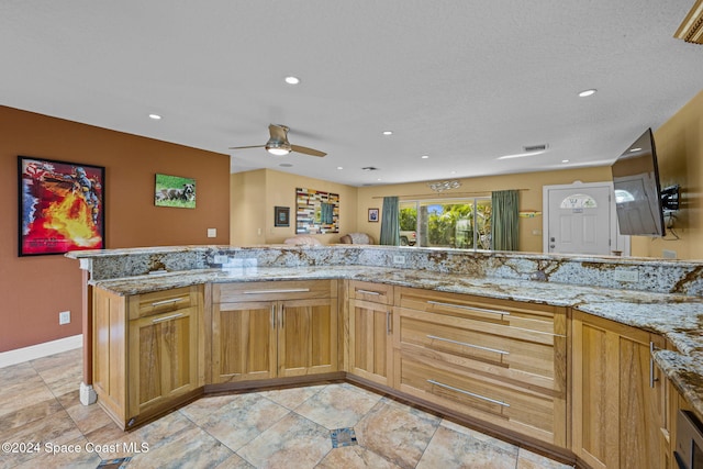 kitchen with light stone countertops, a textured ceiling, kitchen peninsula, and ceiling fan