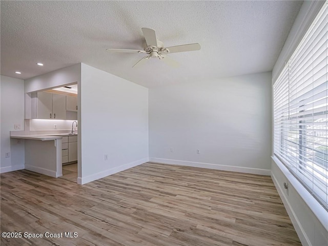 2800 Indian River Blvd Unit L-2, Vero Beach, FL 32960 - unfurnished living room featuring a textured ceiling, light wood-style floors, ceiling fan, baseboards, and a sink