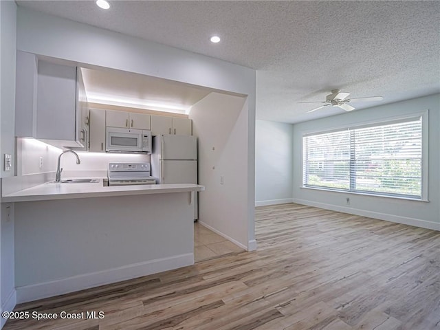 2800 Indian River Blvd Unit L-2, Vero Beach, FL 32960 - kitchen featuring white appliances, a sink, a peninsula, light wood-type flooring, and a ceiling fan