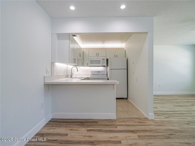 2800 Indian River Blvd Unit L-2, Vero Beach, FL 32960 - kitchen featuring white appliances, a sink, a peninsula, light wood finished floors, and light countertops