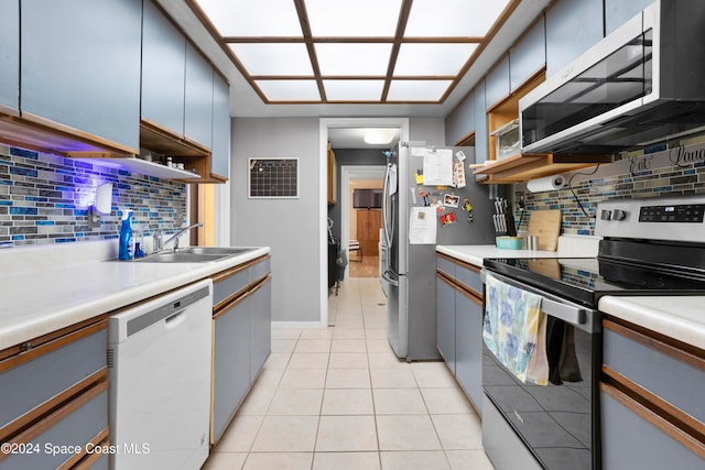 kitchen featuring backsplash, sink, light tile patterned floors, and appliances with stainless steel finishes