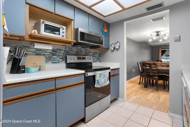 kitchen with blue cabinetry, stainless steel appliances, a textured ceiling, decorative backsplash, and light tile patterned floors