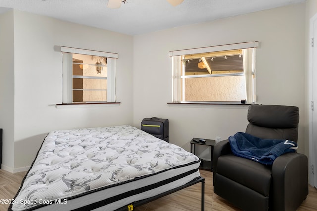 bedroom with ceiling fan, multiple windows, and light hardwood / wood-style flooring