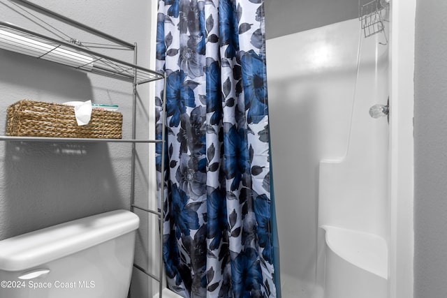 bathroom featuring a shower with shower curtain and toilet