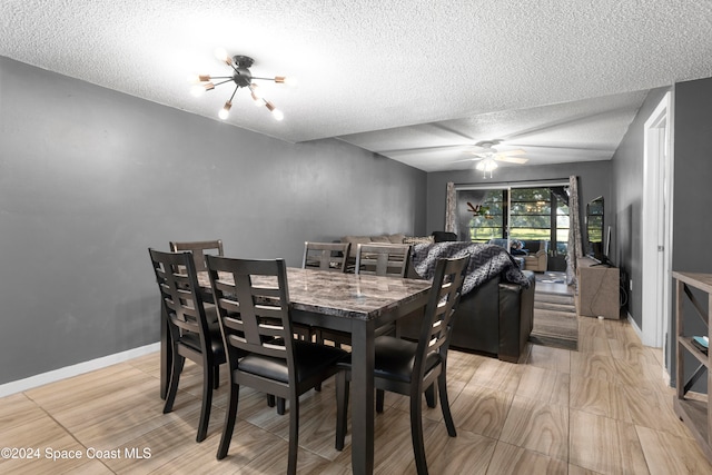 dining room featuring ceiling fan with notable chandelier and a textured ceiling