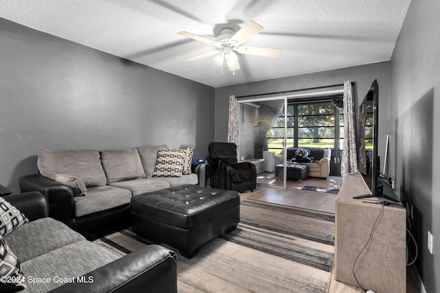 living room featuring ceiling fan, light hardwood / wood-style floors, and a textured ceiling