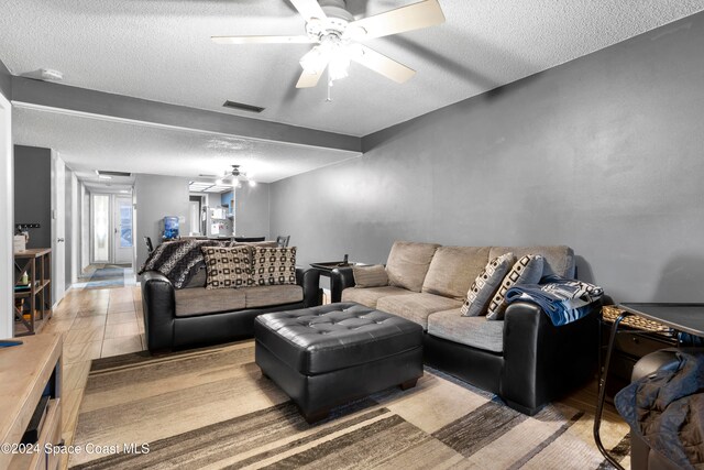 living room featuring ceiling fan and a textured ceiling