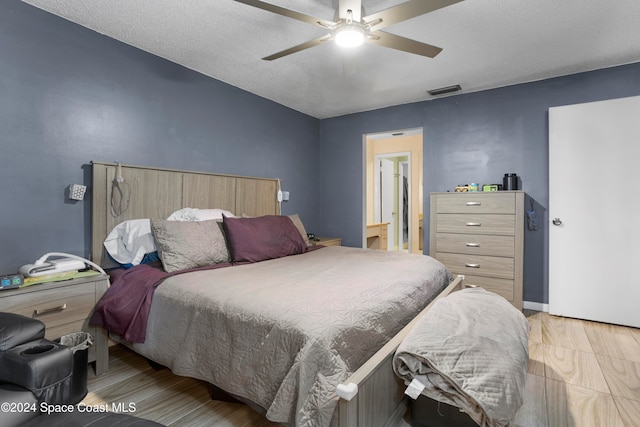 bedroom with ceiling fan, a textured ceiling, and light wood-type flooring