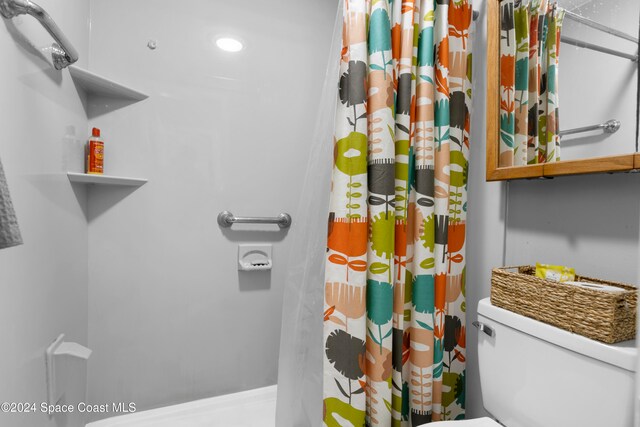 bathroom with a shower with shower curtain and toilet