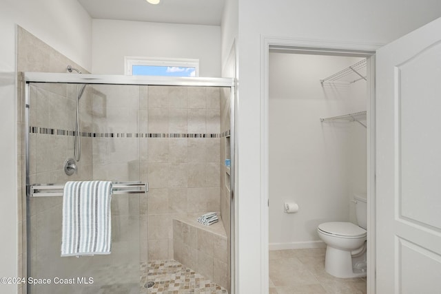 bathroom with tile patterned flooring, toilet, and an enclosed shower