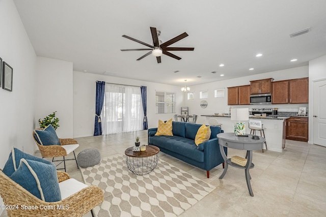 tiled living room featuring ceiling fan with notable chandelier