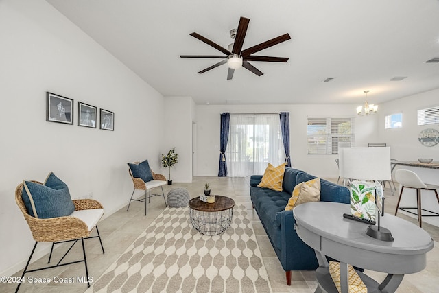 tiled living room with ceiling fan with notable chandelier and plenty of natural light