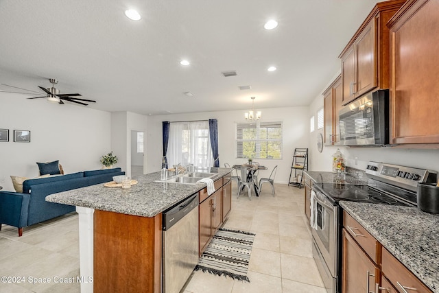 kitchen featuring a kitchen island with sink, ceiling fan with notable chandelier, sink, stone countertops, and stainless steel appliances