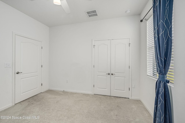 unfurnished bedroom with a closet, light colored carpet, and ceiling fan