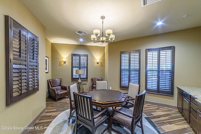 dining area featuring dark hardwood / wood-style flooring, a textured ceiling, and a chandelier