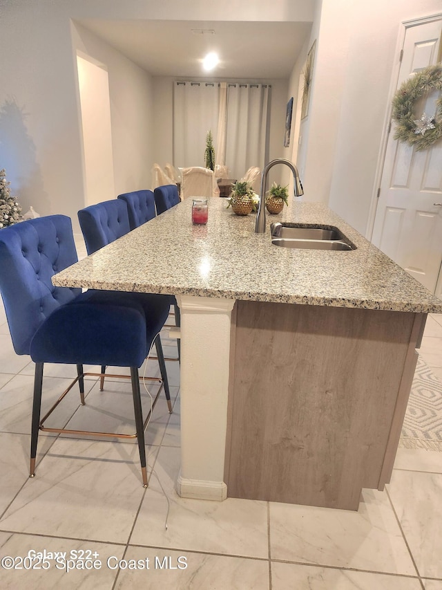 1631 Wake Forest Rd NW, Palm Bay, FL 32907 - kitchen with a sink, a breakfast bar, a kitchen island with sink, and light stone counters