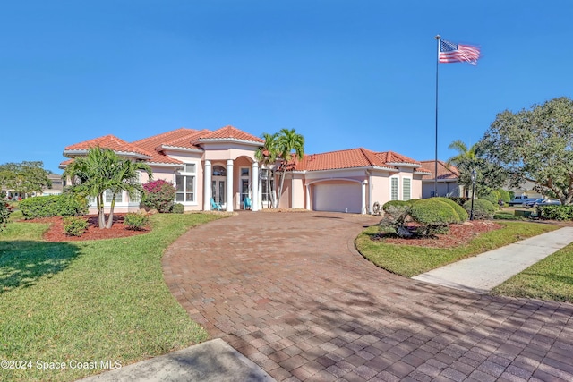 mediterranean / spanish home featuring a garage and a front lawn