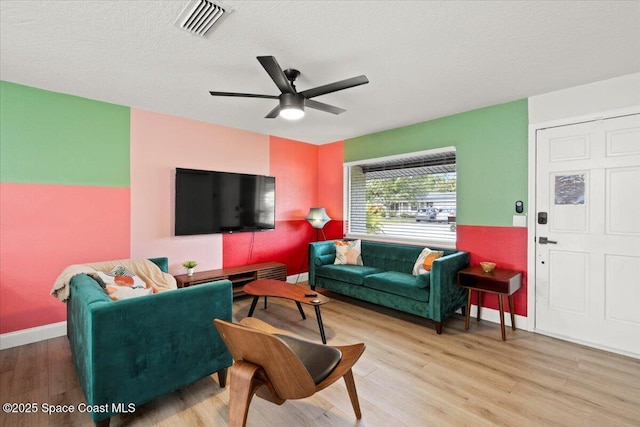 living room with ceiling fan, light hardwood / wood-style flooring, and a textured ceiling