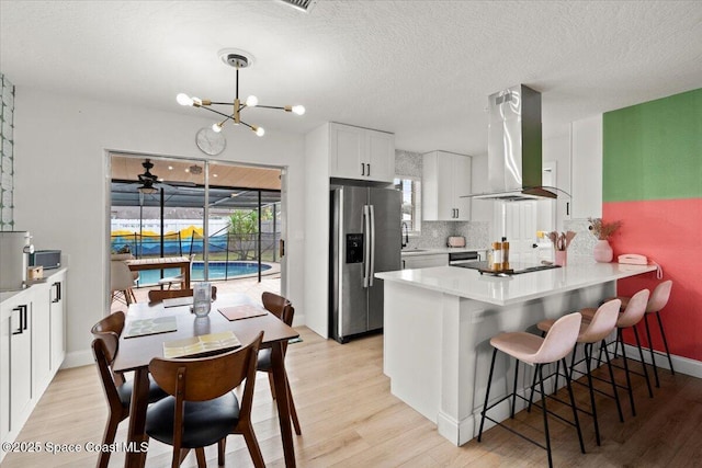 kitchen with ventilation hood, stainless steel refrigerator with ice dispenser, decorative backsplash, white cabinetry, and kitchen peninsula