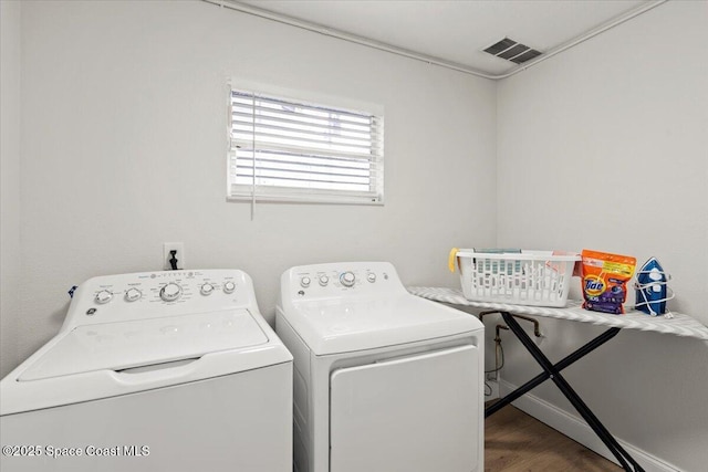 laundry room with washer and clothes dryer and dark wood-type flooring