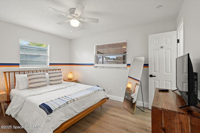 bedroom featuring ceiling fan, light wood-type flooring, and a textured ceiling