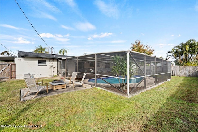 rear view of house with a yard, a fenced in pool, glass enclosure, and an outdoor fire pit