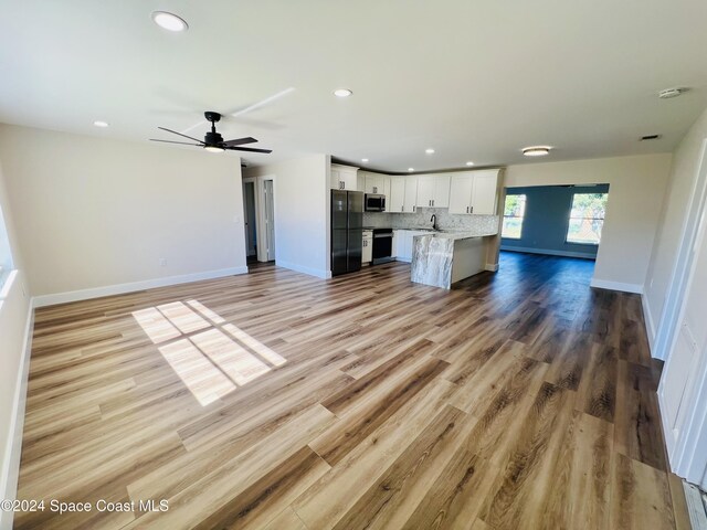 unfurnished living room featuring ceiling fan, light wood-type flooring, and sink