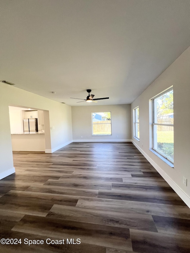 unfurnished living room with ceiling fan and dark wood-type flooring