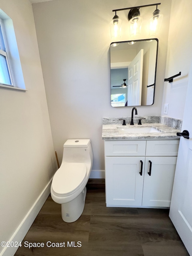 bathroom with ceiling fan, toilet, wood-type flooring, and vanity