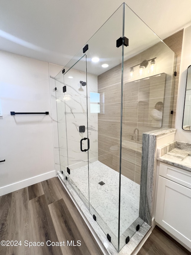 bathroom with hardwood / wood-style flooring, vanity, and an enclosed shower