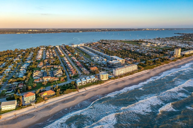 aerial view at dusk with a water view and a view of the beach