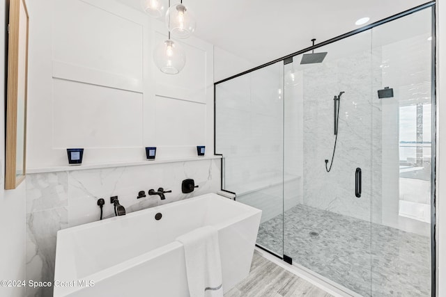 bathroom featuring shower with separate bathtub, tile walls, and wood-type flooring