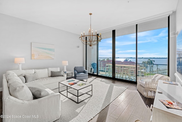 living room with light wood-type flooring, a water view, an inviting chandelier, and floor to ceiling windows