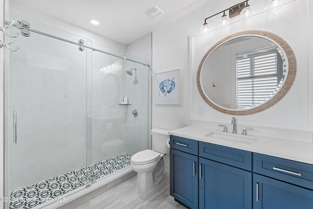 bathroom featuring a shower with door, vanity, hardwood / wood-style floors, and toilet