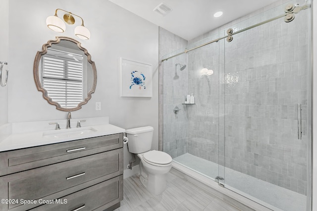 bathroom featuring a shower with door, vanity, and toilet