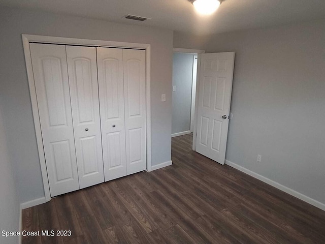 unfurnished bedroom with dark hardwood / wood-style flooring and a closet