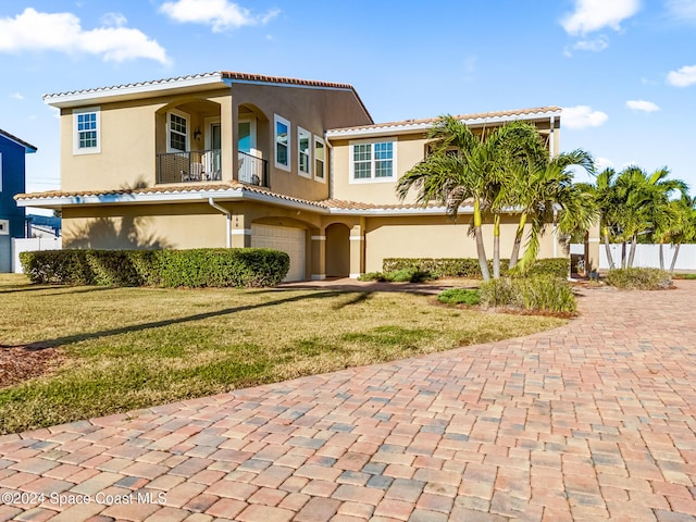 mediterranean / spanish-style house with a garage and a front lawn