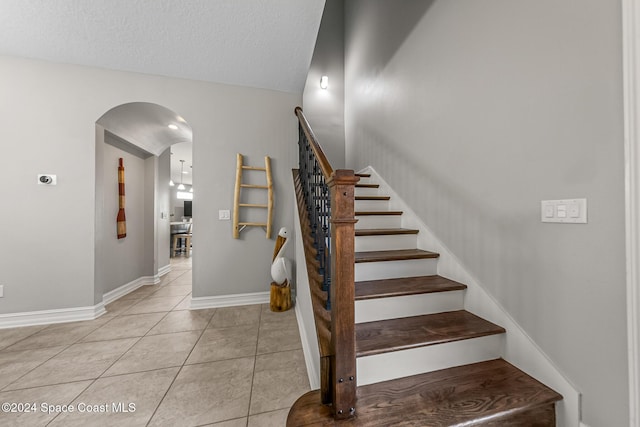 staircase with tile patterned floors and a textured ceiling