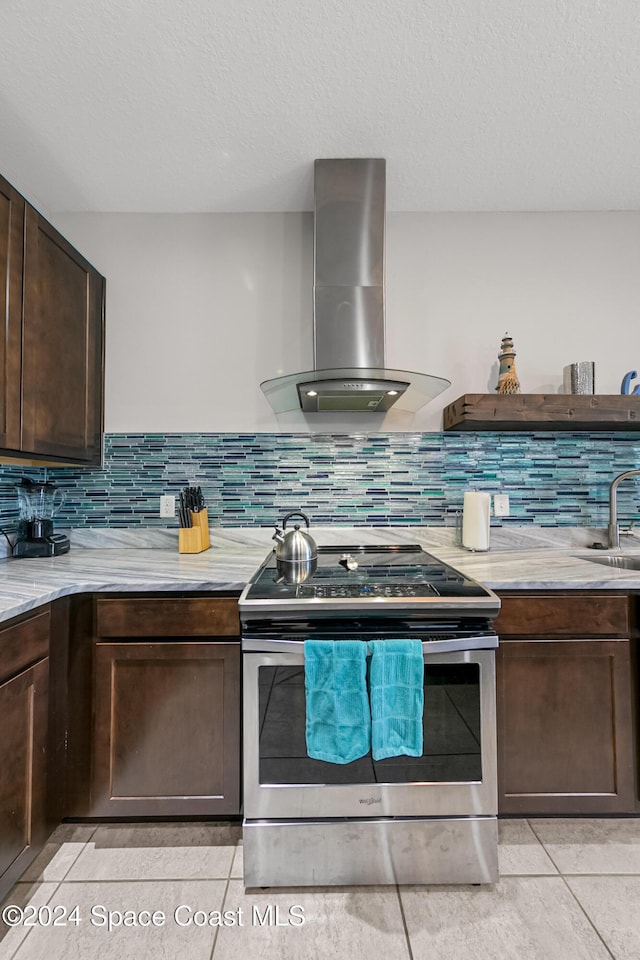 kitchen featuring backsplash, wall chimney exhaust hood, dark brown cabinetry, double oven range, and light tile patterned flooring