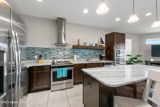 kitchen with sink, wall chimney exhaust hood, tasteful backsplash, decorative light fixtures, and stainless steel appliances