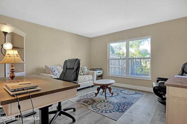 office with light hardwood / wood-style floors and a textured ceiling