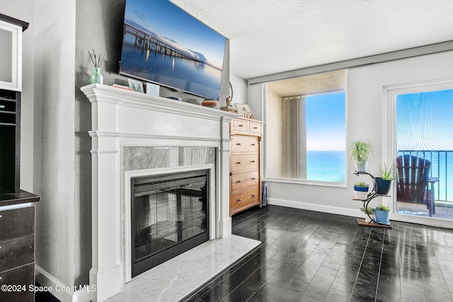 living room with a textured ceiling, a water view, a wealth of natural light, and dark hardwood / wood-style floors