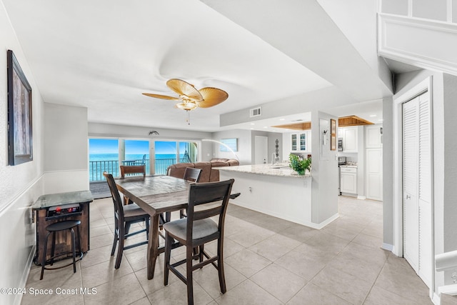 tiled dining area with ceiling fan and a water view