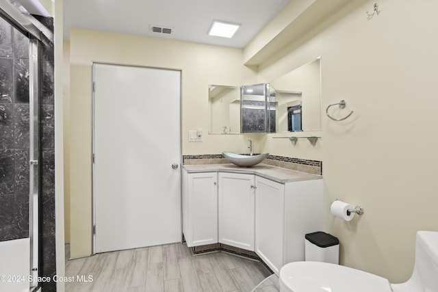 bathroom with hardwood / wood-style flooring, vanity, toilet, and walk in shower