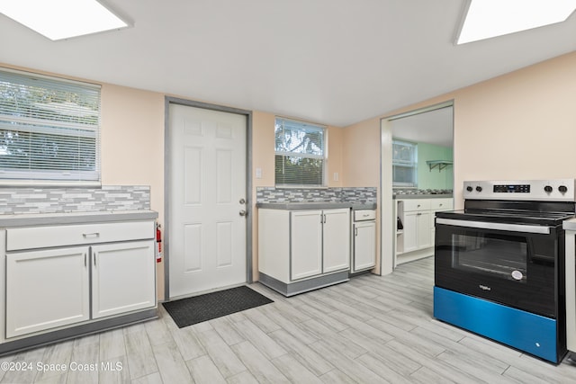 kitchen featuring decorative backsplash, white cabinetry, light hardwood / wood-style floors, and stainless steel electric range